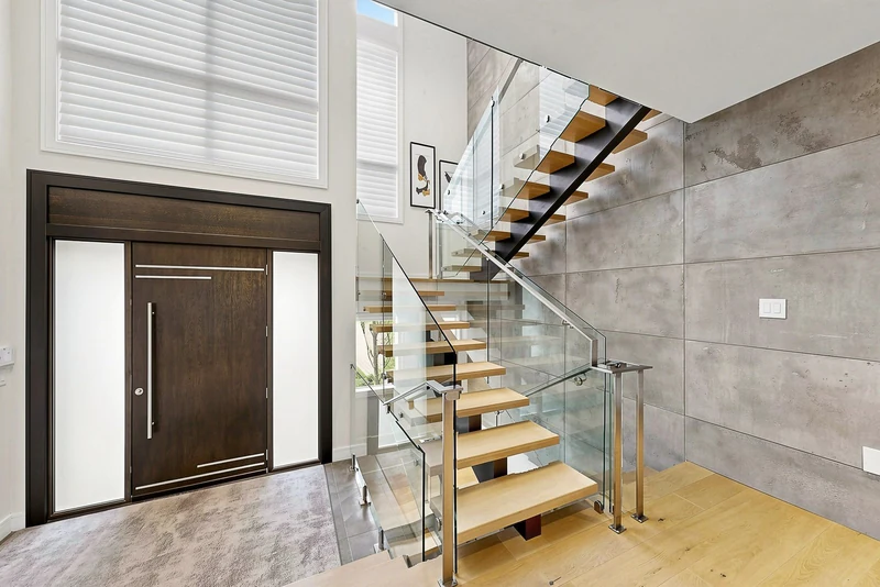 Entry and floating oak stair against the concrete wall