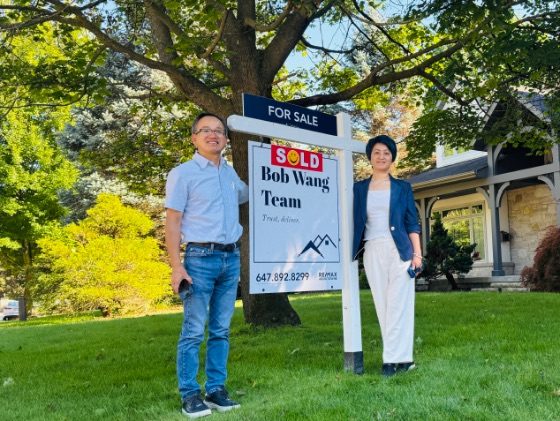 Bob Wang and Elisa Zhang in front of a SOLD sign